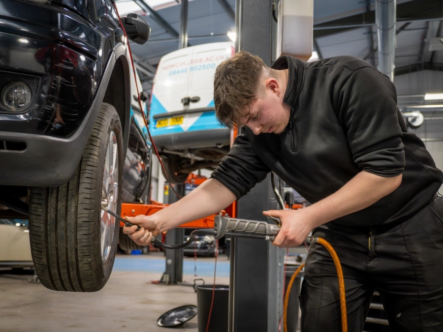Apprentice pumping up a tyre on a car