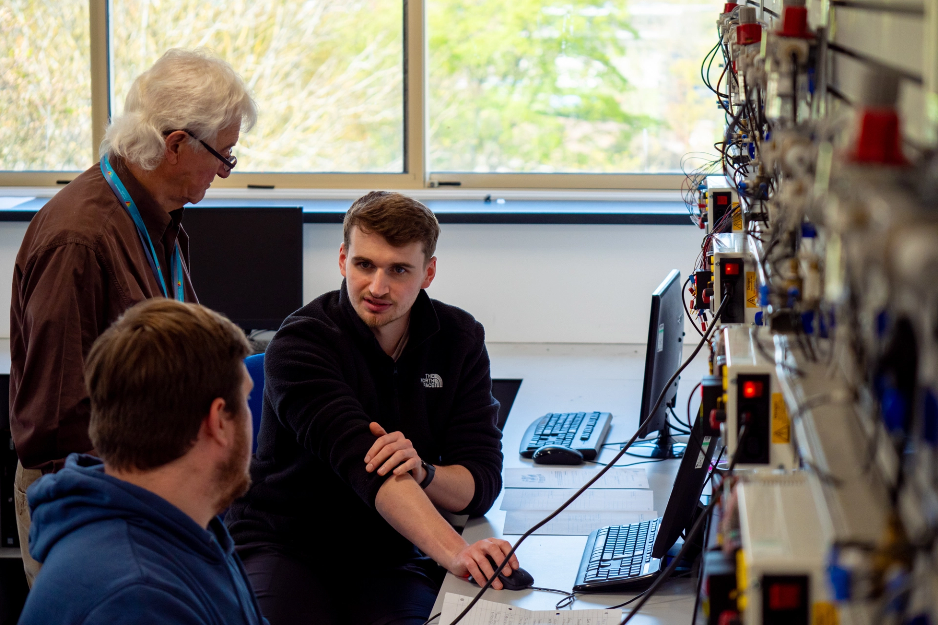A tutor helping two students who are working on computers