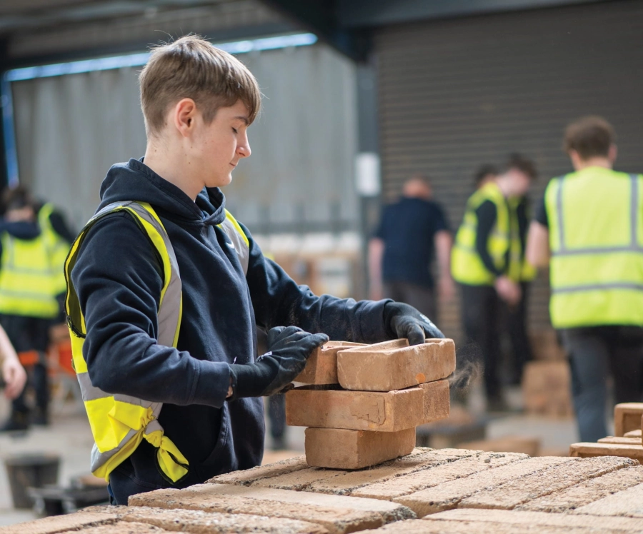 Student piling bricks in construction workshop