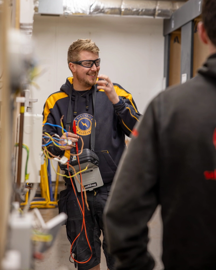 Student holding wires in a workshop talking to peers