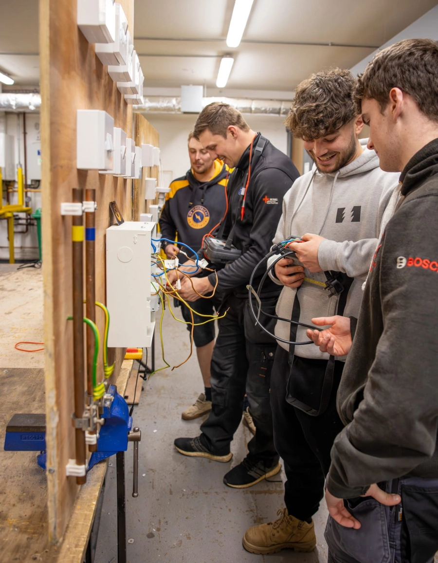 Group of students wiring a plug socket in workshop