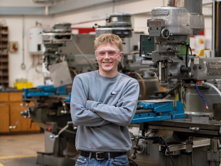 Student stood with arms crossed in front of engineering equipment