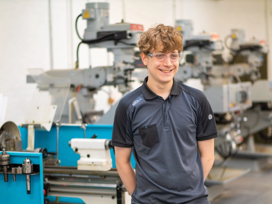 Student smiling in engineering workshop in front of machinery