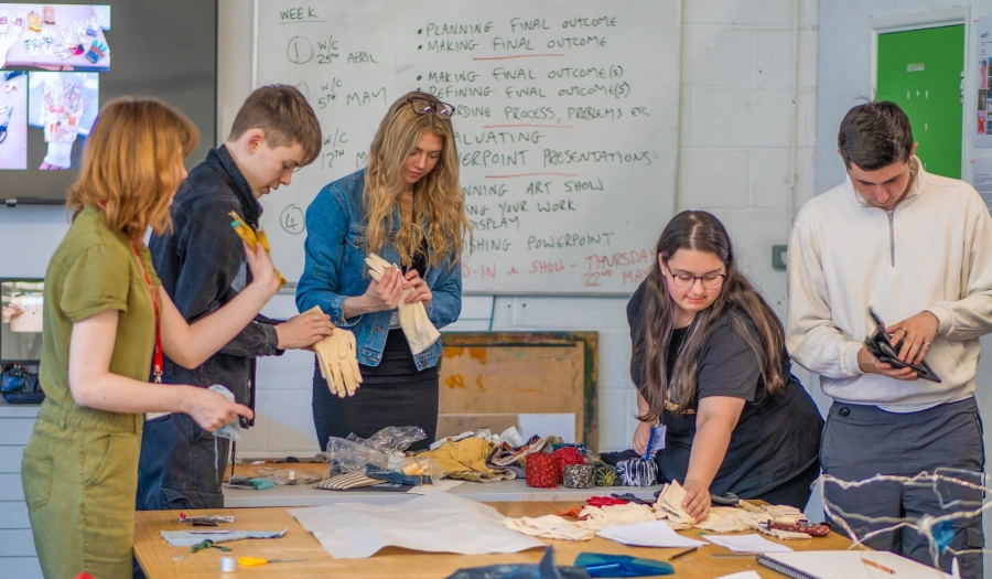 5 students stood around a table looking at different gloves to choose