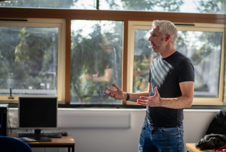 Man stood in a classroom giving a talk