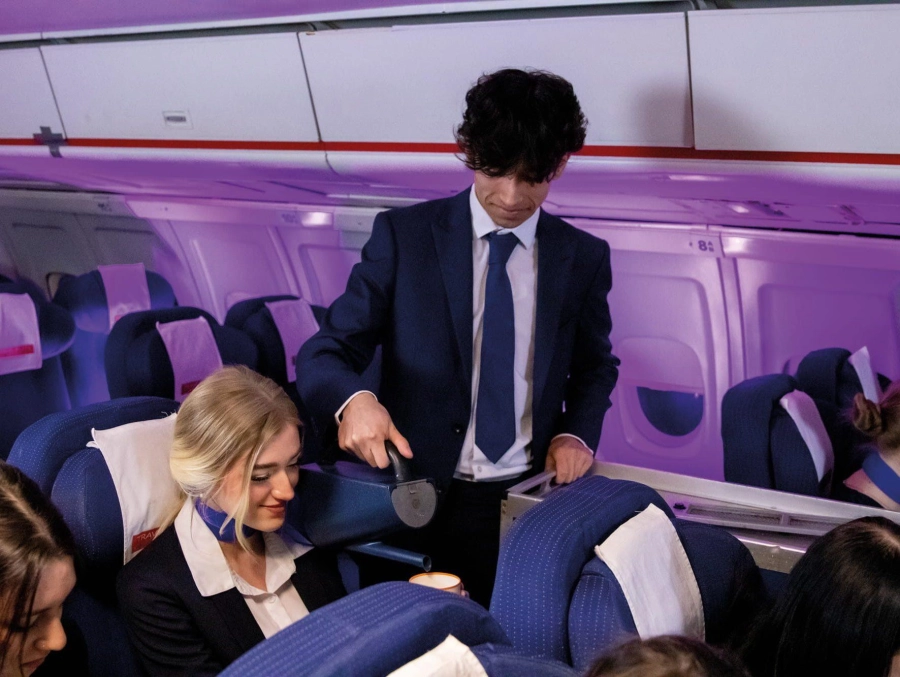 Student serving someone a drink in mock air cabin