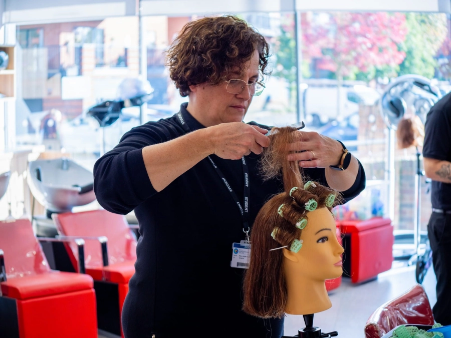 Student using rollers on mannequin head