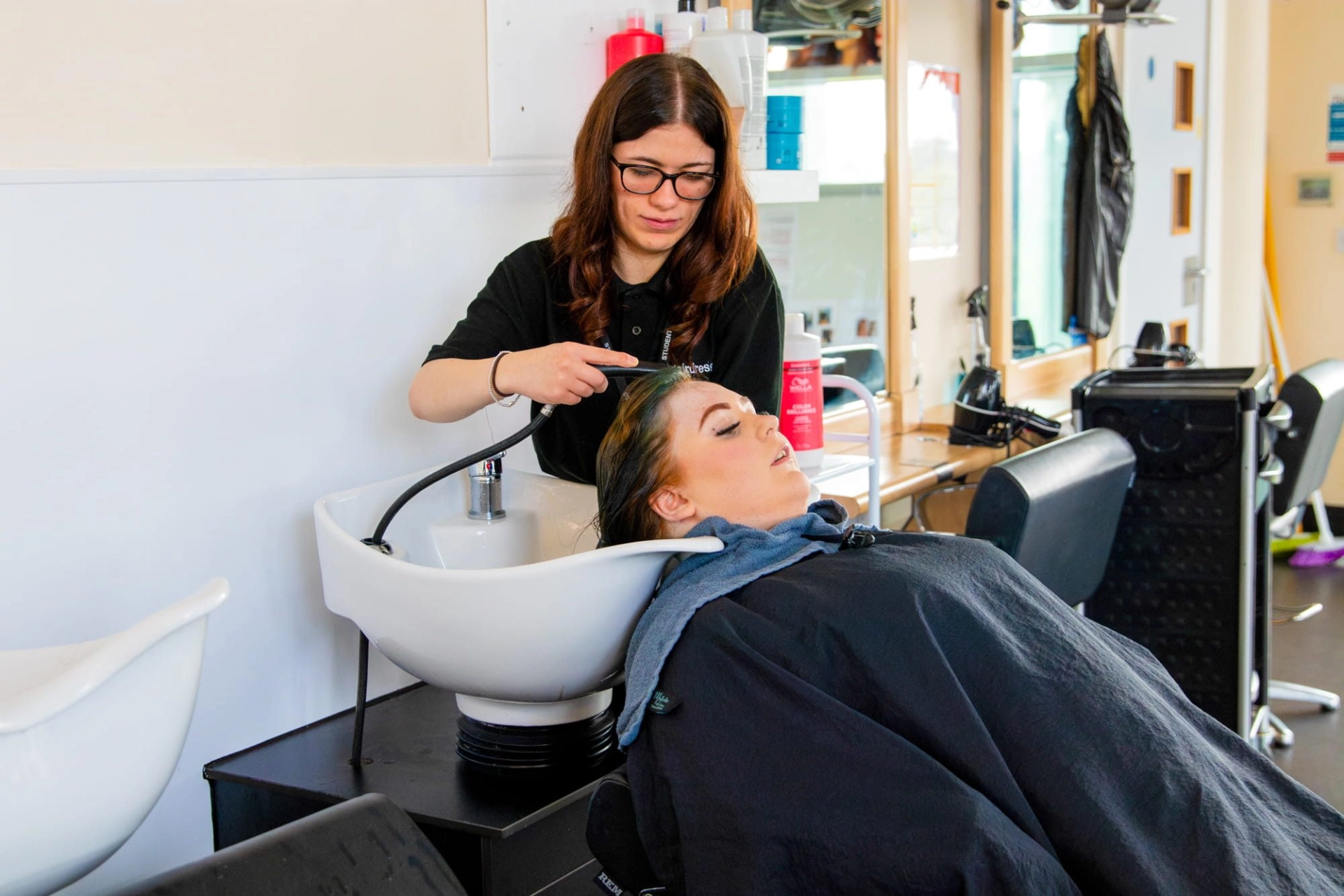 Student in salon washing someones hair